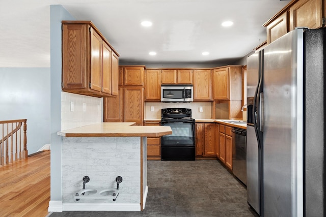 kitchen with light countertops, a peninsula, appliances with stainless steel finishes, and a sink