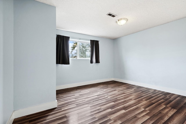 spare room with visible vents, baseboards, a textured ceiling, and wood finished floors