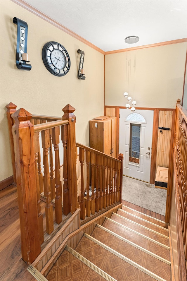 stairs with crown molding, baseboards, and wood finished floors