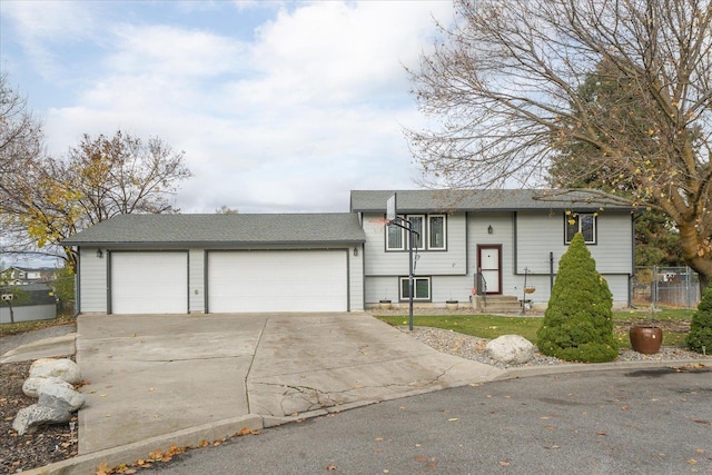 raised ranch featuring fence, driveway, an attached garage, a shingled roof, and entry steps