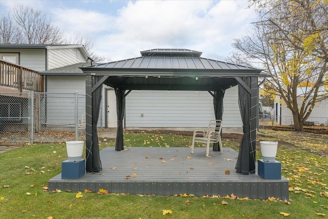 wooden terrace featuring a gazebo, a lawn, and fence