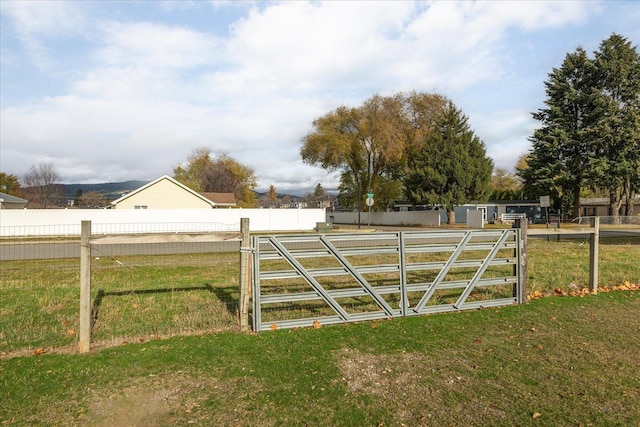 view of gate with a yard and fence