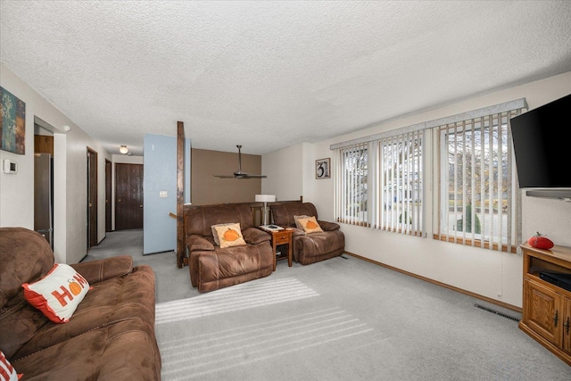 living area featuring a textured ceiling, baseboards, ceiling fan, and carpet floors