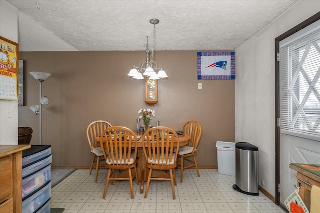 dining area featuring a notable chandelier, light floors, a textured ceiling, and baseboards