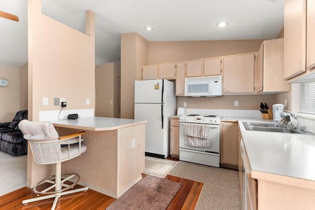 kitchen featuring white appliances, light countertops, a peninsula, and a sink