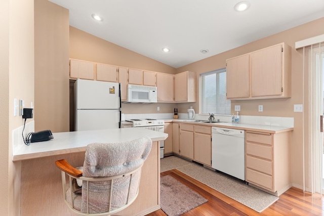 kitchen with white appliances, a peninsula, light countertops, and vaulted ceiling