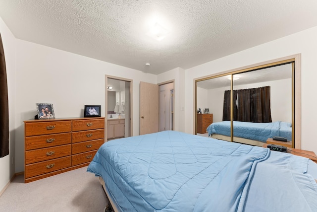 bedroom featuring a closet, light colored carpet, ensuite bathroom, and a textured ceiling