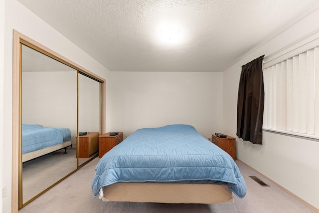 carpeted bedroom featuring visible vents, a closet, and a textured ceiling