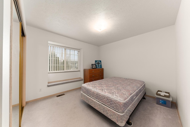 bedroom featuring visible vents, baseboards, a textured ceiling, and carpet flooring