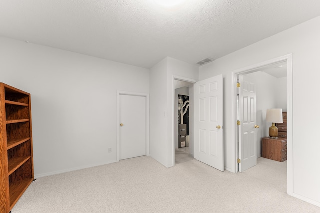 bedroom featuring visible vents, light colored carpet, and a textured ceiling