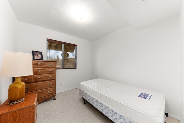 bedroom with baseboards, light carpet, and a textured ceiling