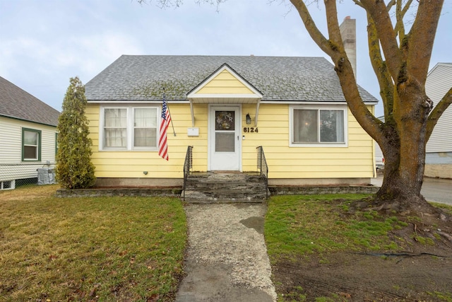 bungalow-style house featuring roof with shingles, a front lawn, and entry steps