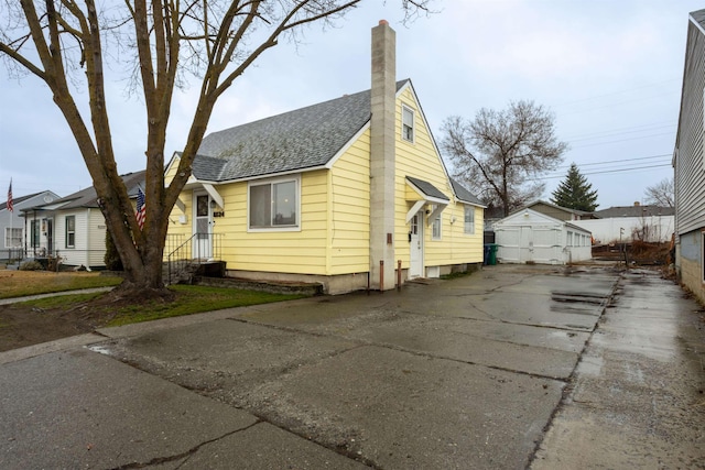 view of home's exterior with driveway, roof with shingles, and a chimney