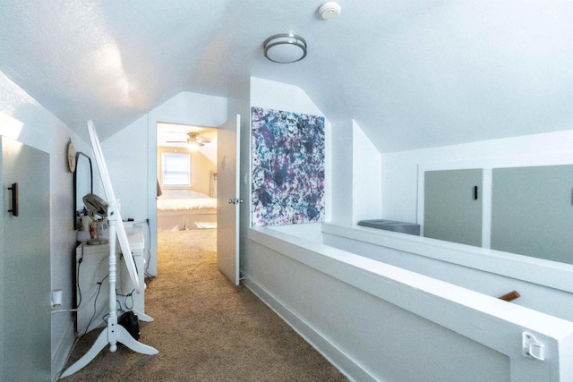 hallway with vaulted ceiling, carpet floors, and a textured ceiling