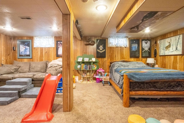 bedroom with visible vents, multiple windows, wood walls, and carpet flooring