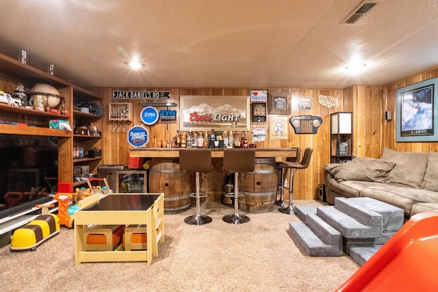 interior space featuring visible vents, carpet, wooden walls, and a bar