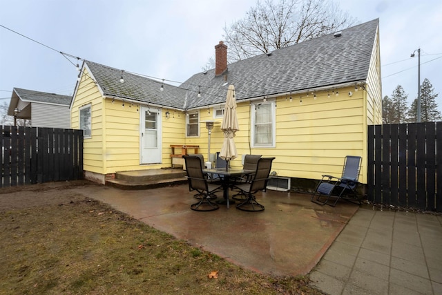 back of house featuring a chimney, roof with shingles, a patio, and fence