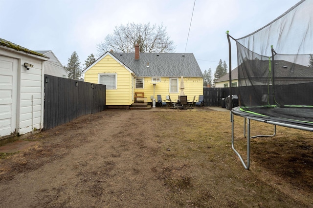 back of property featuring entry steps, a trampoline, and fence