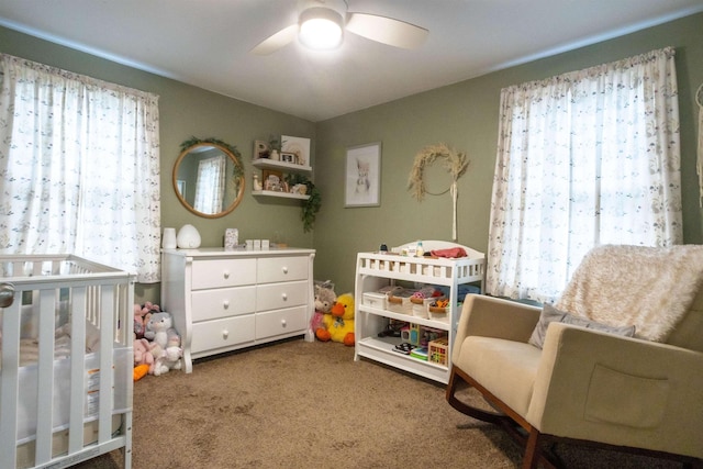 bedroom with a nursery area, carpet floors, and ceiling fan