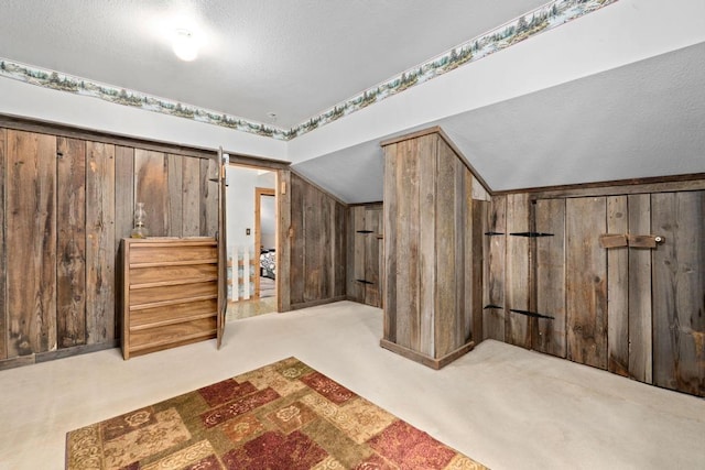 bonus room featuring wood walls, a textured ceiling, carpet, and vaulted ceiling