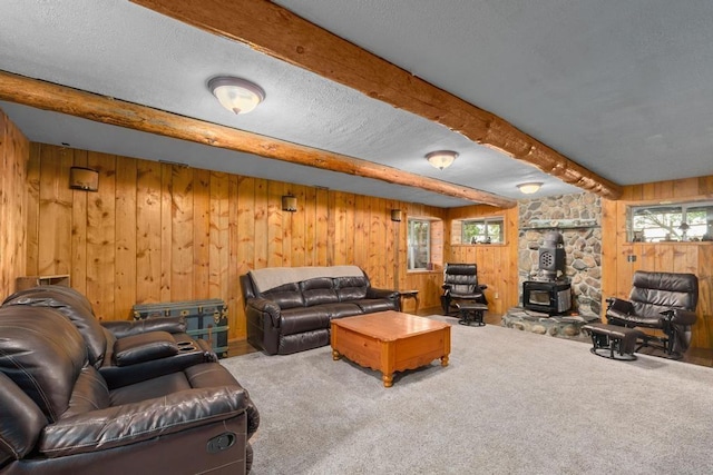 living area featuring beamed ceiling, a textured ceiling, a wood stove, and carpet floors