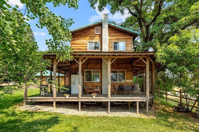 rear view of house featuring a lawn, a chimney, and fence