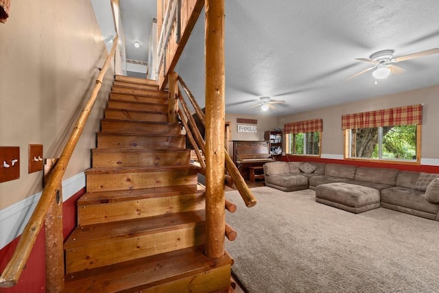 stairway featuring a textured ceiling, carpet floors, and ceiling fan