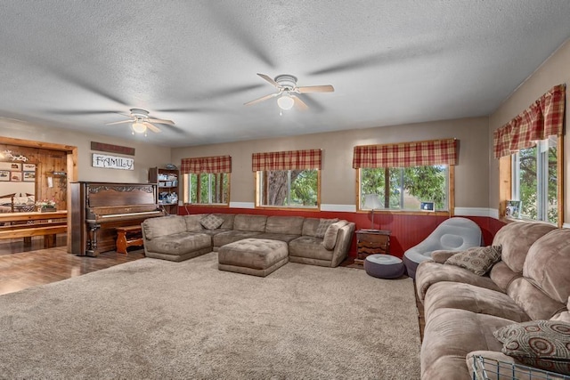 living room with a textured ceiling, wainscoting, and ceiling fan