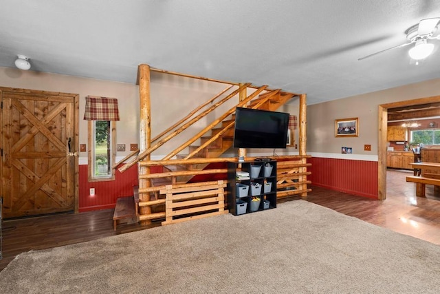 living room with a wainscoted wall, stairway, a ceiling fan, and wood finished floors