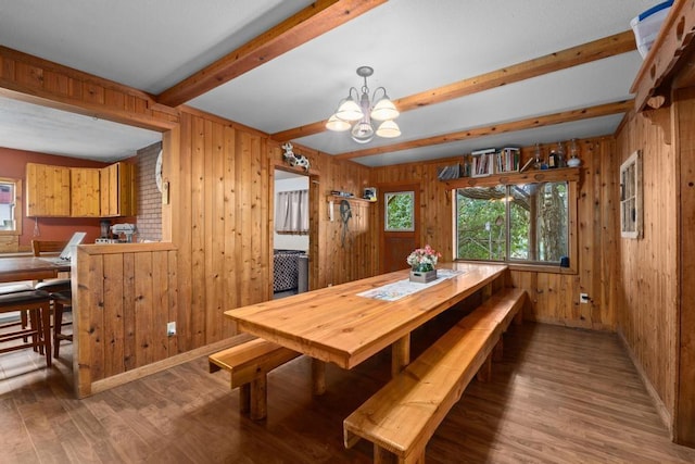 dining space featuring beam ceiling, wood finished floors, wood walls, and a chandelier