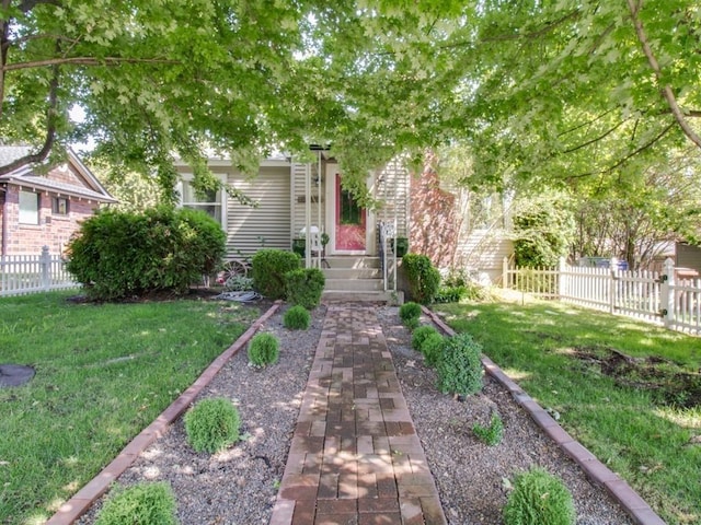 view of property hidden behind natural elements featuring a front lawn and fence