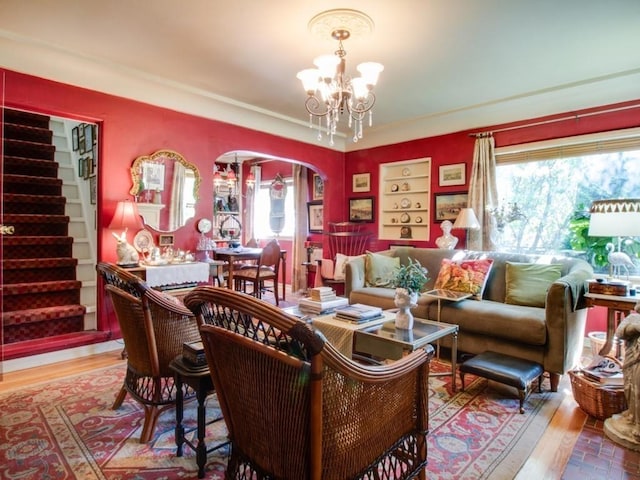 interior space featuring built in shelves, wood finished floors, an inviting chandelier, arched walkways, and stairs