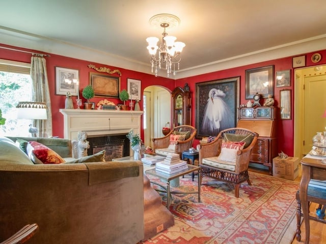 living room featuring wood finished floors, a notable chandelier, a fireplace, and arched walkways