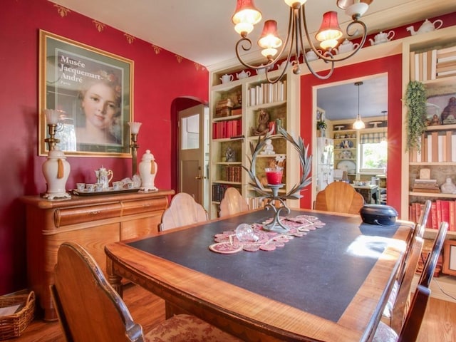 dining space with a notable chandelier, wood finished floors, and arched walkways