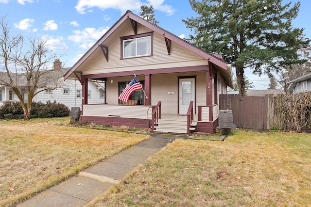 bungalow-style house featuring a front lawn, fence, and covered porch