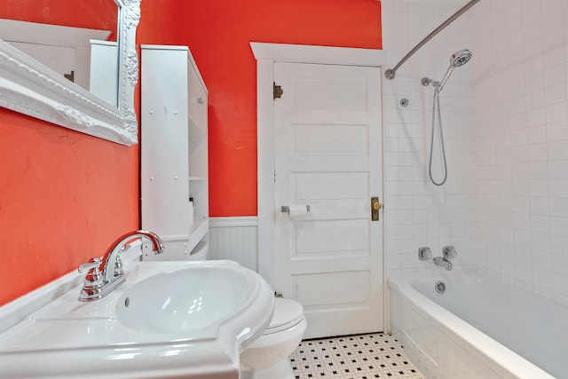 full bathroom with toilet, washtub / shower combination, a wainscoted wall, and a sink