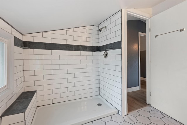 bathroom with tile patterned flooring, vaulted ceiling, and tiled shower