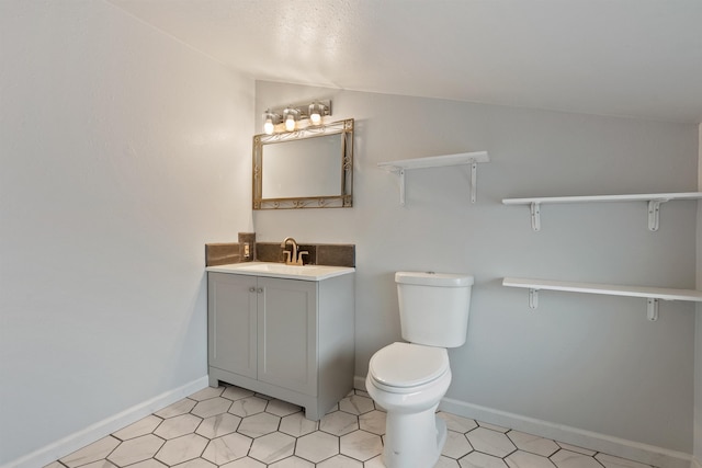 bathroom with vanity, vaulted ceiling, toilet, and baseboards