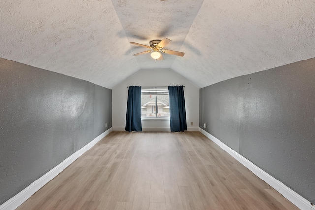 bonus room featuring a textured wall, a textured ceiling, a ceiling fan, and wood finished floors