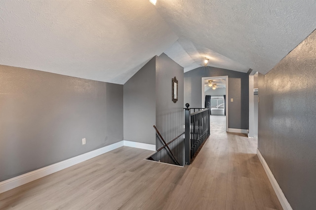 additional living space with baseboards, lofted ceiling, and wood finished floors