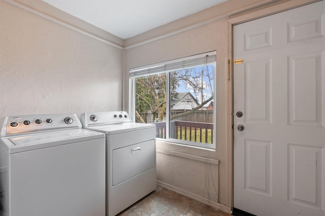 clothes washing area with laundry area, a textured wall, and independent washer and dryer