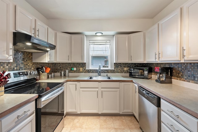 kitchen featuring backsplash, under cabinet range hood, white cabinets, stainless steel appliances, and a sink