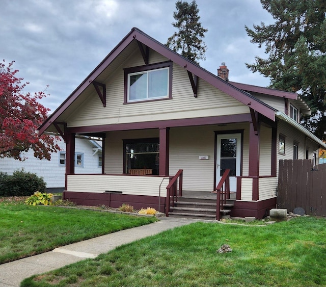 bungalow-style home featuring a front lawn, a porch, and a chimney