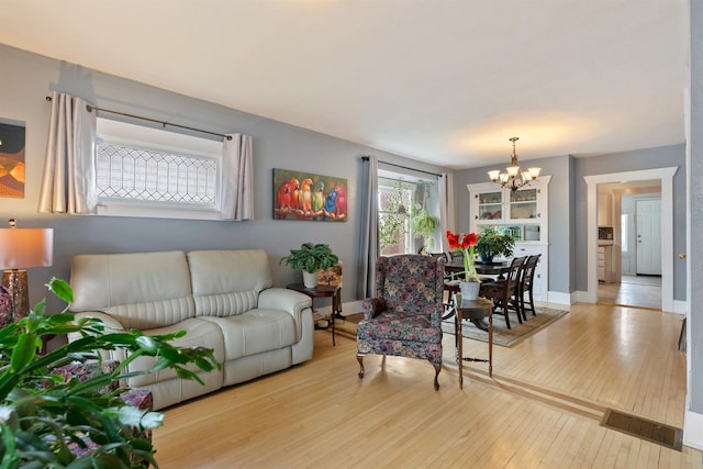 living area with hardwood / wood-style floors, an inviting chandelier, baseboards, and visible vents