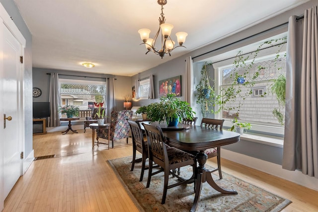 dining room with a wealth of natural light, a notable chandelier, and light wood finished floors