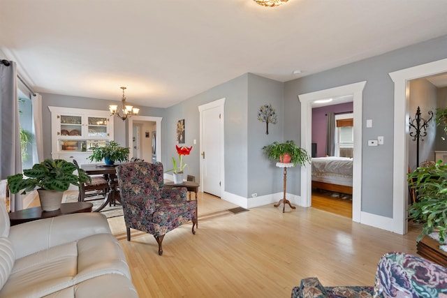 living room featuring a notable chandelier, baseboards, and light wood-type flooring