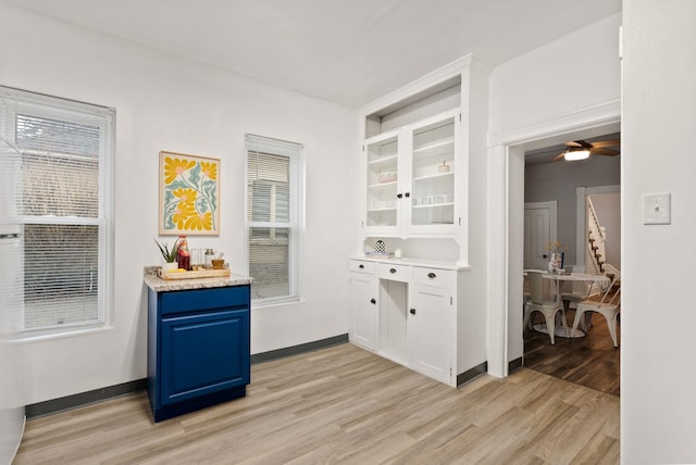 bar featuring light wood-style flooring, baseboards, and ceiling fan