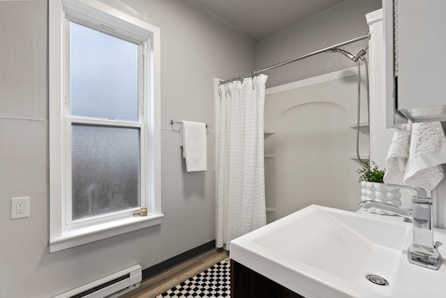 bathroom with a sink, a baseboard heating unit, wood finished floors, and a wealth of natural light