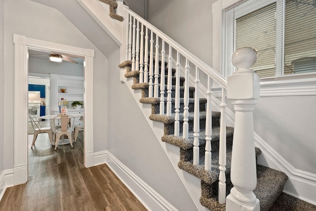 stairway featuring a ceiling fan, wood finished floors, and baseboards