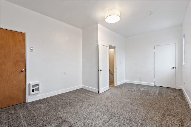 carpeted empty room featuring baseboards and heating unit